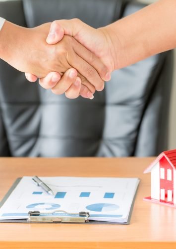 Side view hands of agent and client shaking hands after signed contract buy new apartment.